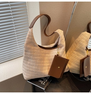 Detail of cream straw woven shoulder bag featuring brown leather strap and small pouch