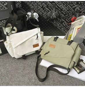Detail of cargo-style messenger bags in cream and sage green with functional buckles