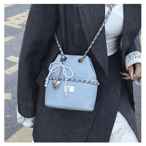 Detail of light blue lychee pattern bucket bag with pearl bow and silver heart charm