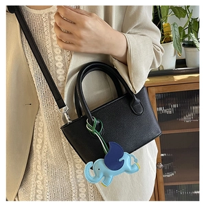 Detail of black lychee grain leather mini bucket bag with a cute blue elephant charm