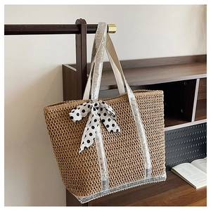 Détail d'un sac cabas en paille avec bandoulière à paillettes et ruban à pois