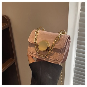 Macro detail of pink crocodile texture girl's handbag with gold chain and round buckle