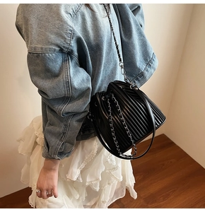 Detail showing pleated texture of the black bucket bag with chain and leather strap