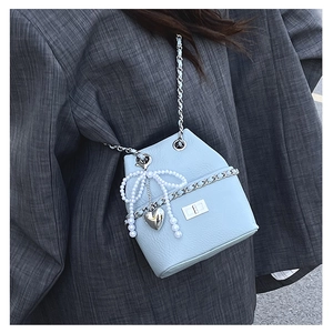 Detail of light blue pebble leather bucket bag with pearl bow and silver chain