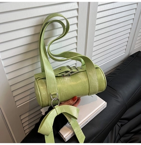 Close-up of light green cylindrical Boston bag with textured leather and bow charm