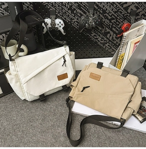 Detail of canvas messenger bags in cream and khaki with secure plastic buckle closures