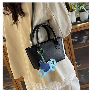Detail of black pebbled leather tote bag featuring a cute colorful elephant charm