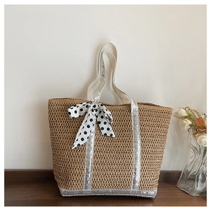 Détail du sac en paille avec poignées à paillettes et un nœud ruban à pois élégant