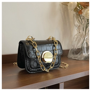 Close-up of girls black crocodile pattern handbag with gold chain and metal buckle