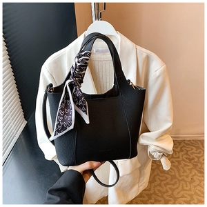 Detail of black lychee grain leather bucket bag with decorative heart print silk scarf
