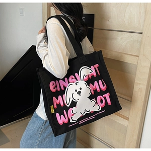 Close-up of black canvas tote bag featuring cute rabbit illustration and pink lettering