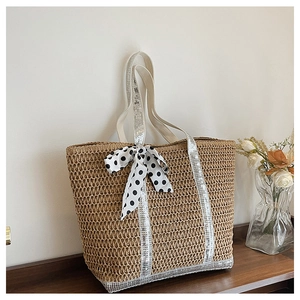 Détail du sac en paille avec bandoulières pailletées et nœud décoratif à pois blancs