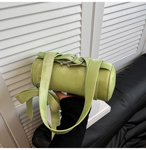 Detail of sage green cylinder bag with matte finish and stylish large bow accent