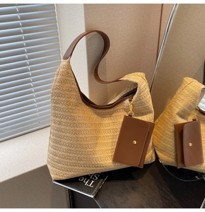 Close-up of beige woven straw shoulder bag with brown leather trim and mirror reflection