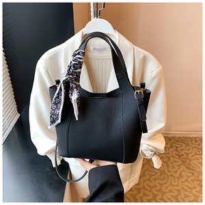 Detail of black pebbled leather bucket bag with gold hardware and heart print scarf handle