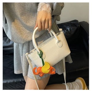 Close-up of white lychee pattern bucket bag with cute orange elephant charm accessory