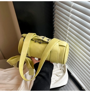 Detail of a bright lime green Boston bag featuring cross straps and metallic buckle hardware