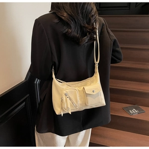 Detailed view of beige hobo bag with functional multi-pockets and vintage utility style