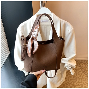 Detail of dark brown lychee leather tote bag with a pink decorative silk scarf