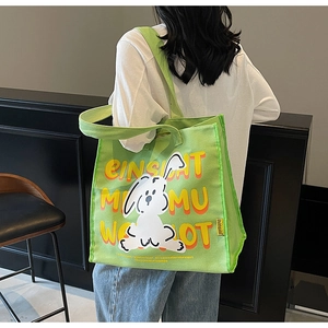 Close-up of green canvas tote bag featuring a cute rabbit illustration and wide strap