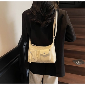 Detail of cream vintage hobo bag with zip and metal buckle pockets on textured faux leather
