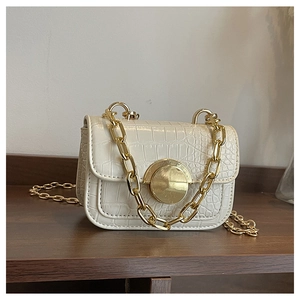 Close-up of cream crocodile pattern bag with gold chain strap and round metallic lock