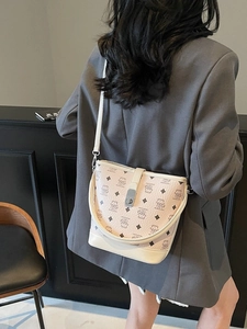 Chic cream bucket bag with bear patterns, crossbody style worn with grey blazer suit