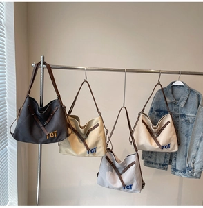 Detail view of large canvas tote bags in four colors with leather straps and TCT embroidery