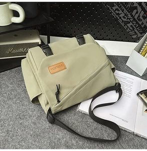 Detail of light green messenger bag with flap buckles and branded leather patch
