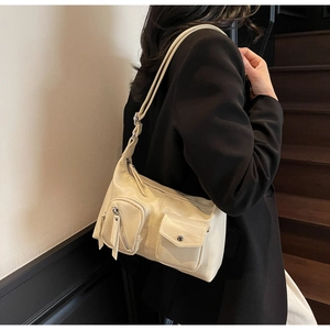 Detail of cream functional shoulder bag showing pockets and faux leather texture