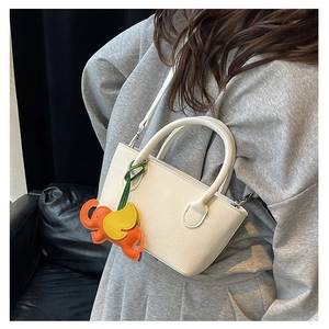 Close-up of white pebble leather bucket bag with cute colorful elephant charm detail