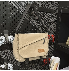 Detail of khaki messenger bag showing brand leather label and diagonal zipper pocket