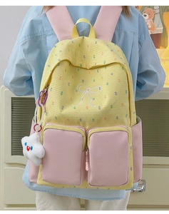 Detail of yellow grid backpack featuring pink pockets and white bow embroidery