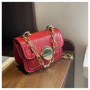 Close-up of red crocodile pattern texture and golden circular lock on child handbag
