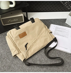 Detail of khaki messenger bag with plastic buckle and adjustable strap on a desk