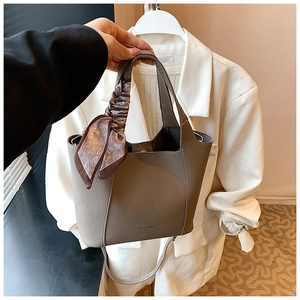 Detail of coffee brown lychee leather bucket bag with heart silk scarf on handle