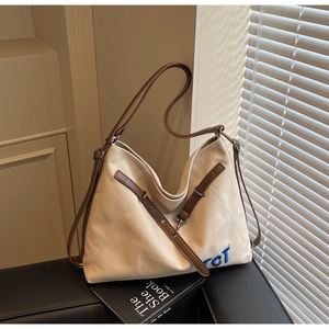 Detailed macro of beige canvas tote bag with brown leather straps and TCT embroidery