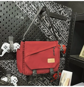 Detailed view of red nylon messenger bag with buckle closures on an industrial background