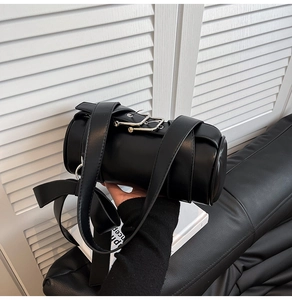 Detail of black cylindrical Boston bag showing matte leather texture and large bow decoration