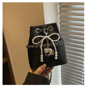 Detail of black leather bucket bag with pearl bow and silver heart pendant decoration