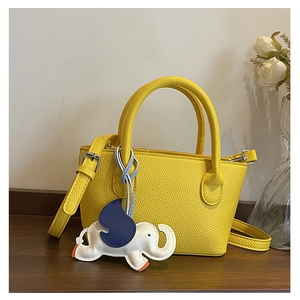Detail of yellow lychee leather handbag with a cute elephant-shaped leather pendant