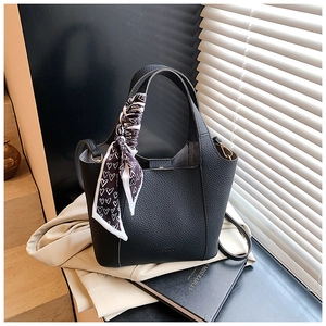 Detail view of black lychee leather handbag with heart print scarf and golden hardware