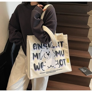 Detailed close-up of a canvas tote bag with cute cartoon dog print and bold typography