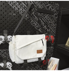 Detail view of off-white canvas messenger bag with black nylon strap and buckle closure