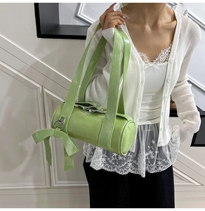 Detail of light green Boston bag with large bow and polished leather texture on model