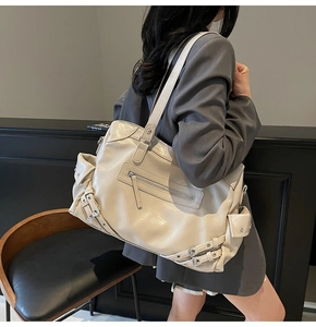 Detail view of a large cream tote bag with multiple pockets and silver hardware