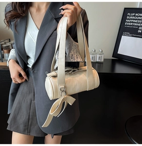 Close-up of cream Boston bag with delicate lace scarf and bow charm detail