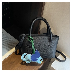 Detail of black lychee grain leather bucket bag with a cute elephant pendant charm
