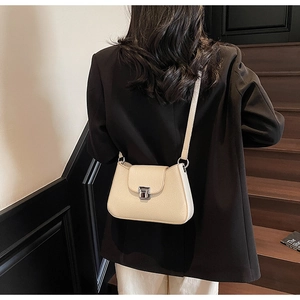 Close-up of light beige leather shoulder bag with silver metallic buckle on a model