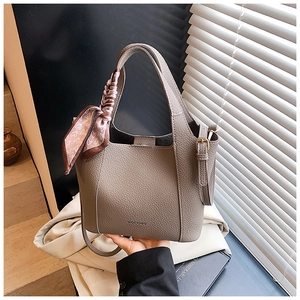 Detail of grey lychee leather bucket bag featuring a silk scarf and top handle